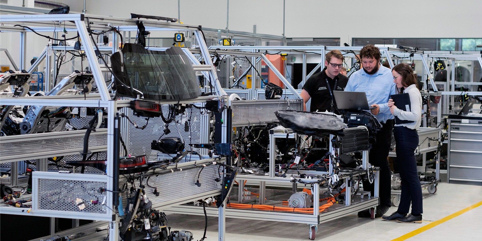 Equipo de ingenieros analizando datos de producción en una línea de montaje automatizada