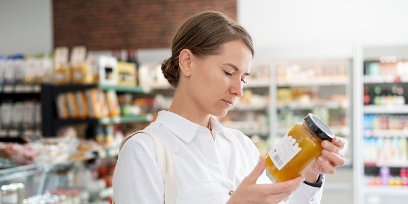Consumidora revisando el etiquetado ambiental de un producto alimentario en un supermercado, ejemplo de la nueva normativa de envases