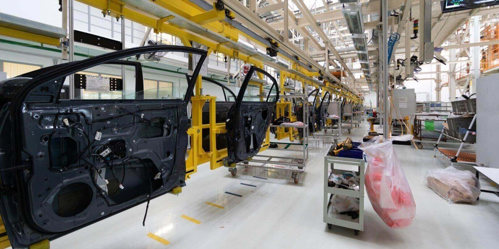 Línea de producción por lotes en planta industrial del sector automotriz con sistemas automatizados y control digital.