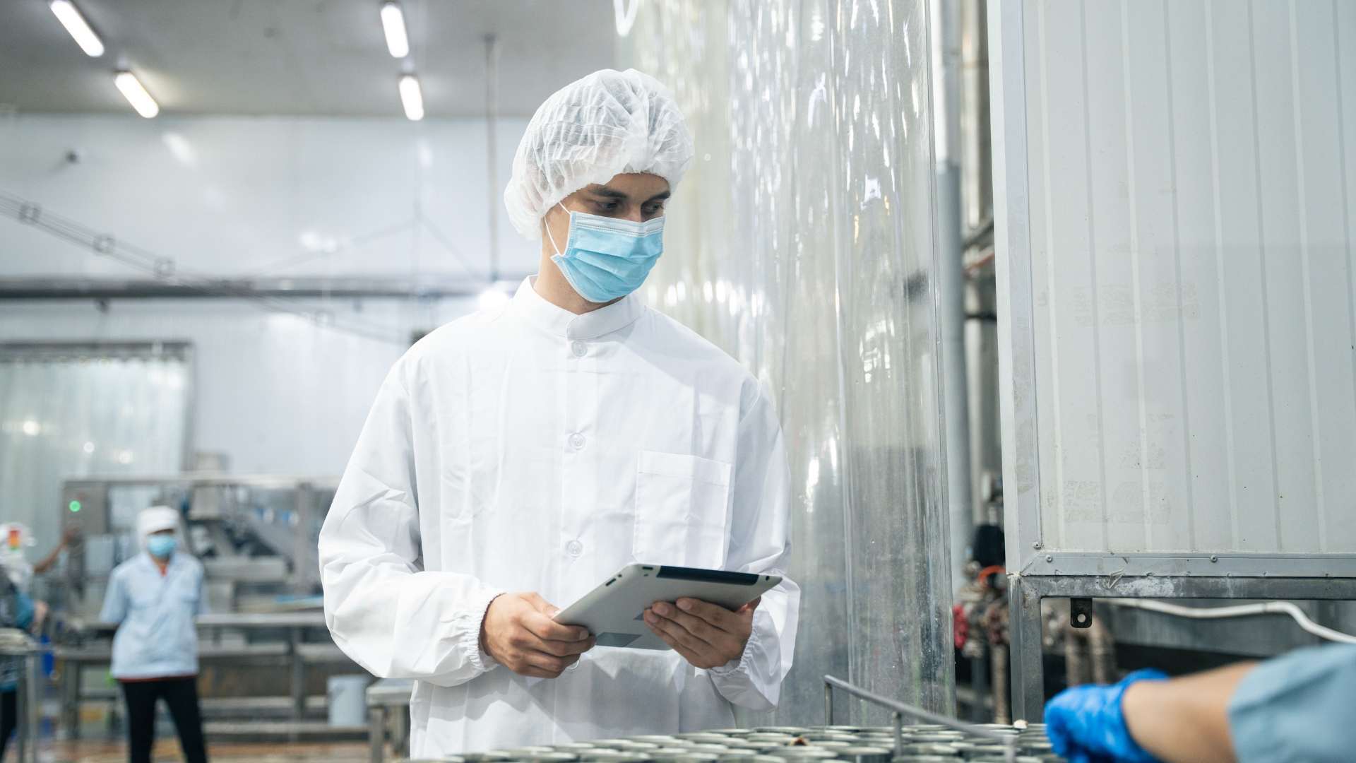 Operario en planta alimentaria consultando trazabilidad y costes por lote en tablet conectada a sistema ERP MES.