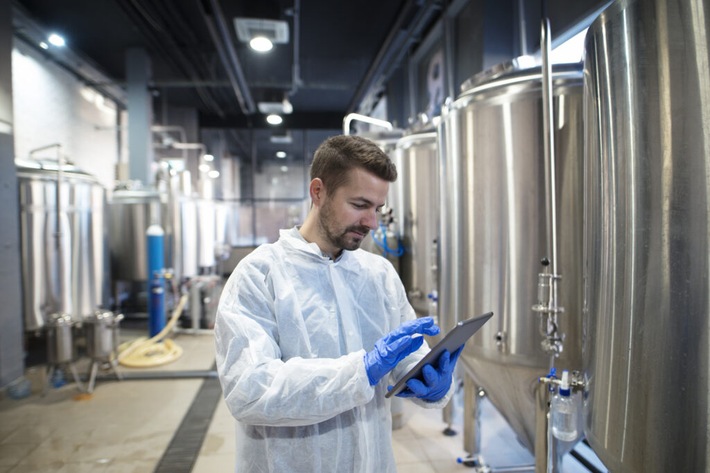 Técnico de calidad industrial revisando datos en tablet dentro de planta alimentaria.