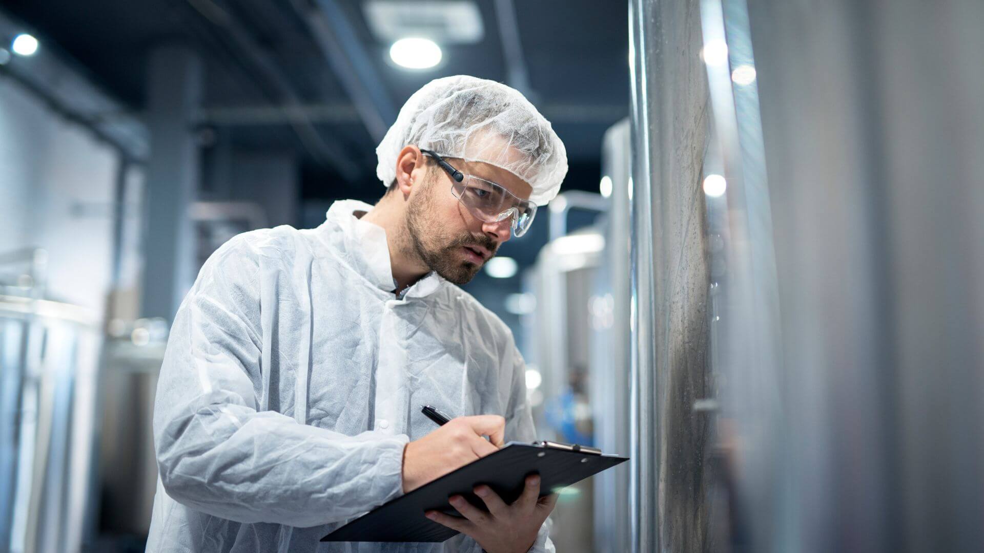 tecnico de calidad en la industria alimentaria inspeccionando un tanque en planta de produccion
