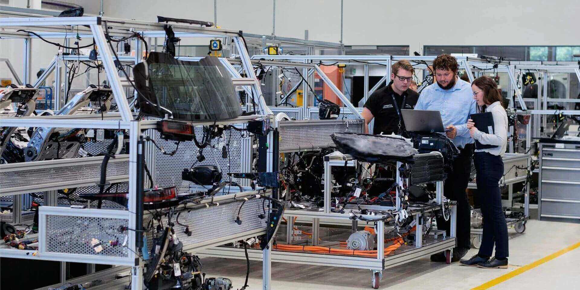 Equipo de ingenieros analizando datos de producción en una línea de montaje automatizada
