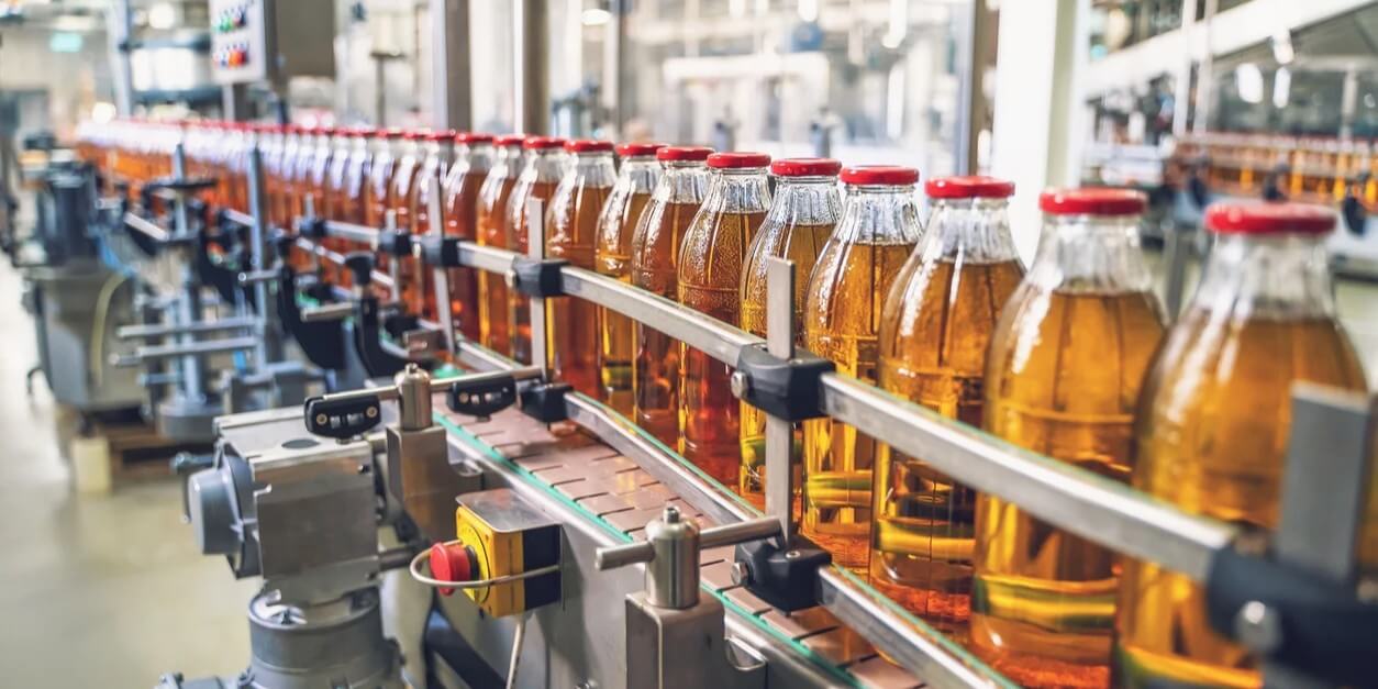 Línea de producción de la industria alimentaria con botellas identificadas.