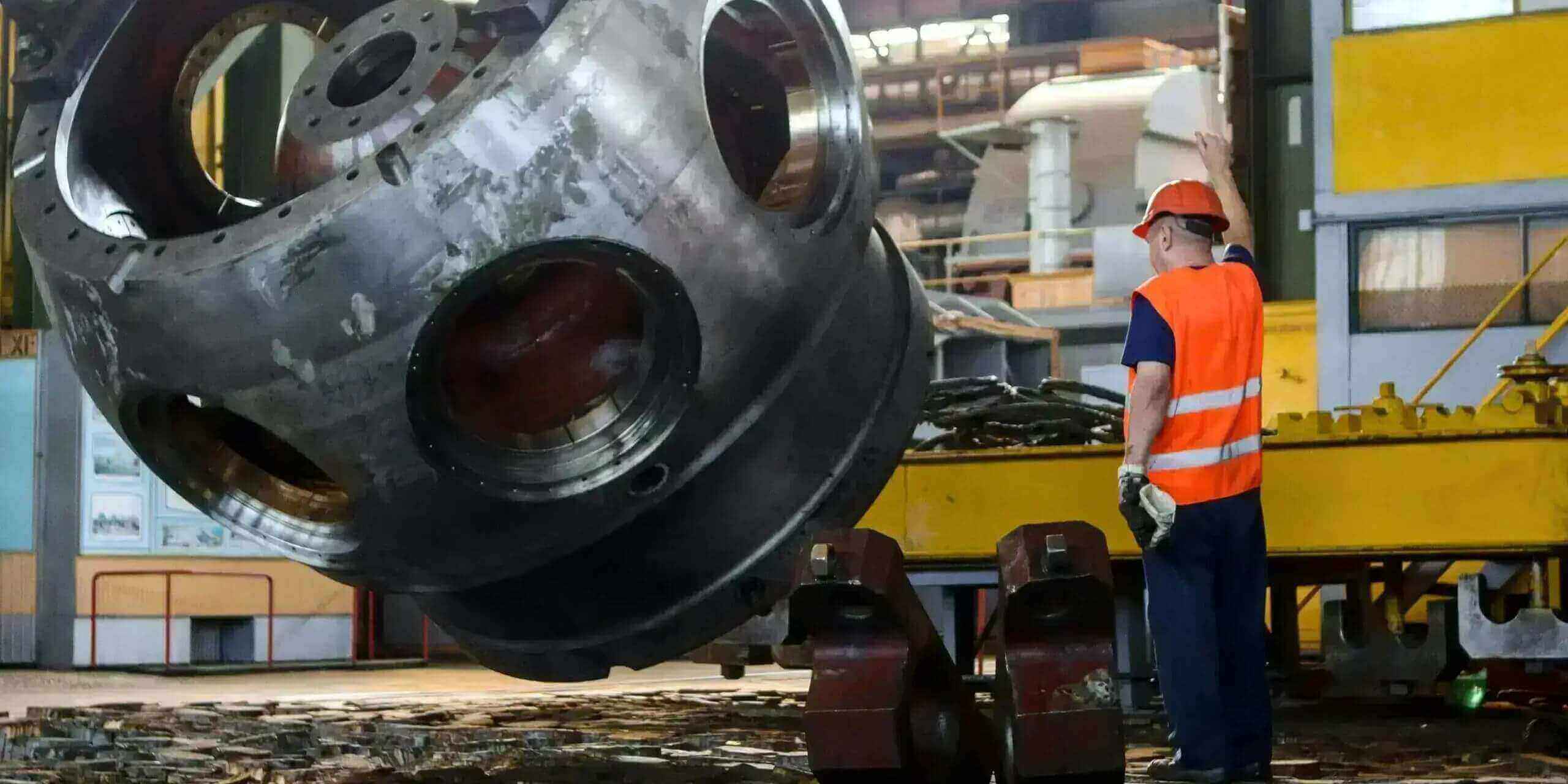 Operario supervisando pieza metálica de gran tamaño en planta de calderería industrial